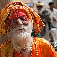 Oude Hare Krishna aanhanger in oranje gekleed voor tempel in Govardhan, India
