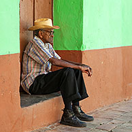 Portret van oude Cubaanse man voor pastel gekleurd huis in de straten van Trinidad, Cuba
