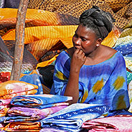 Vrouw verkoopt kleurrijke stoffen op markt in Nouakshott, Mauritanië, Afrika
