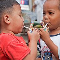 Indonesische kinderen vanaf de leeftijd van drie leren roken met zelfgemaakte pijpen, zogenaamde Popeye Lauts, Jakarta, Java, Indonesië