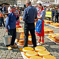 Mensen op houten klompen en kaasbollen op de kaasmarkt in Gouda, Nederland
