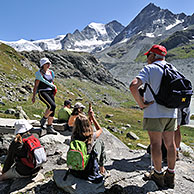 Toeristen / Wandelaars wandelen langs bergpad in de Walliser Alpen, Wallis, Zwitserland

